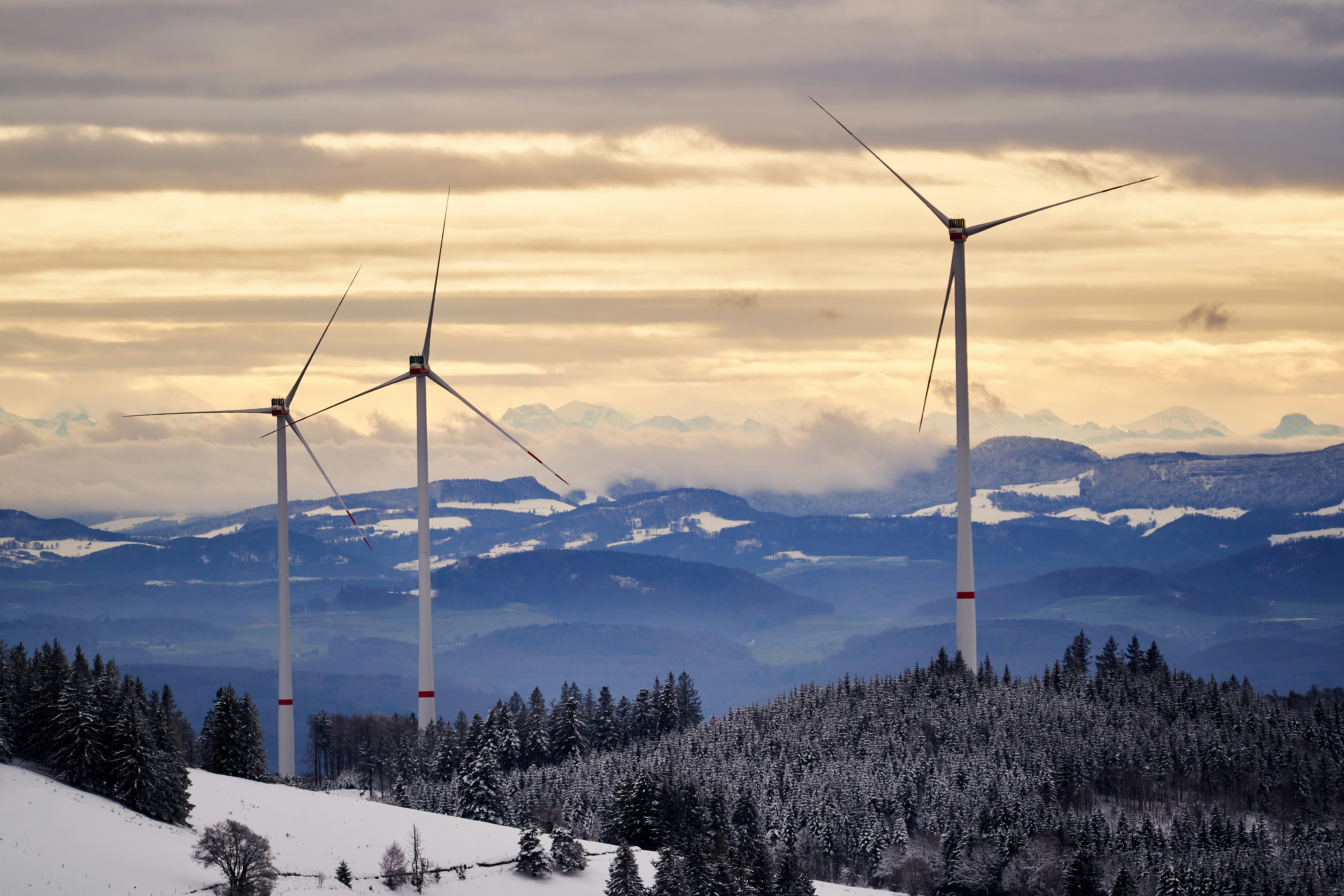 black wind turbines on snow covered mountain during daytime